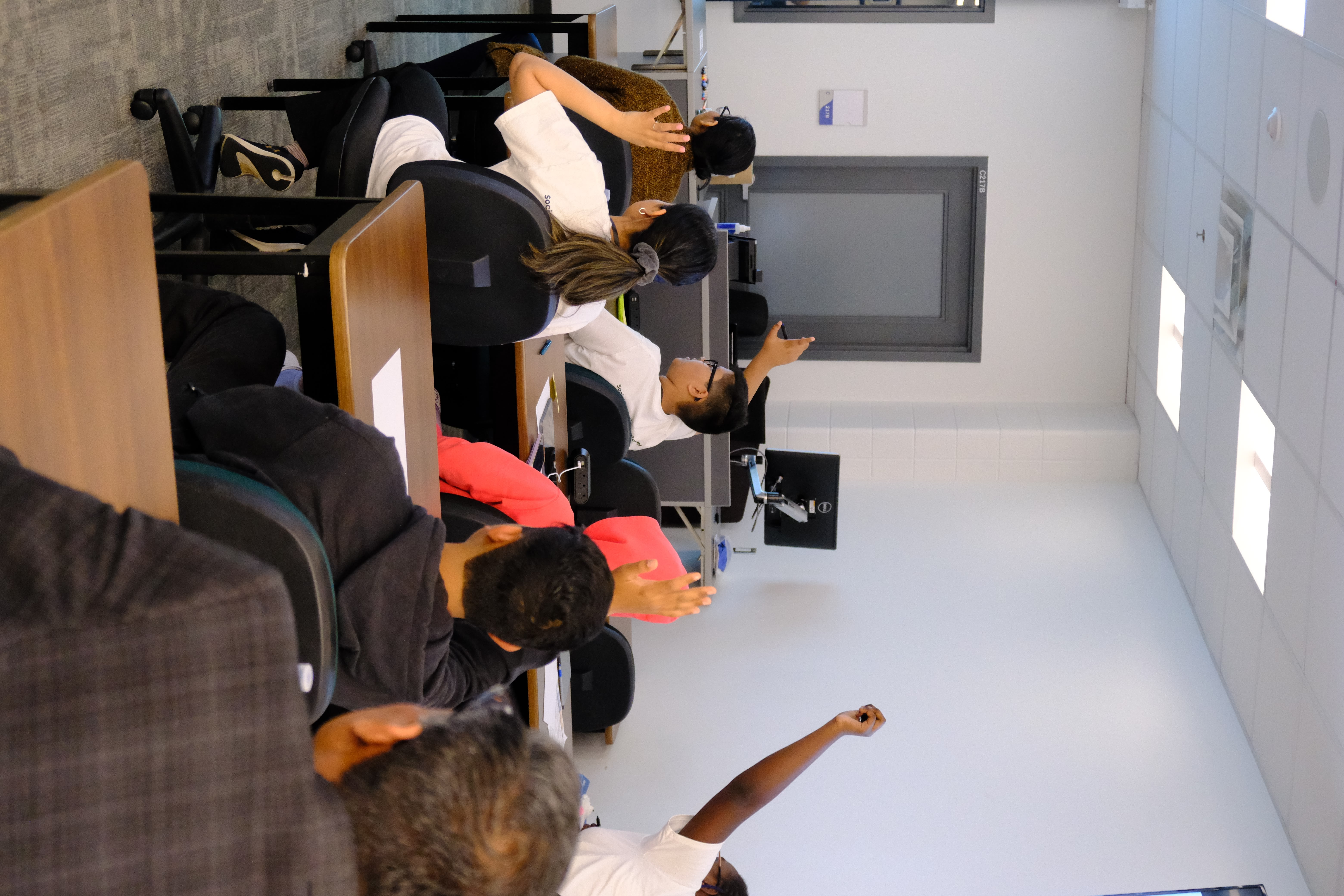 A picture of various youths raising their hands to answer questions during the Learning How to Practice Community Workshop with Dr. Bethany Osborne on June 3, 2025