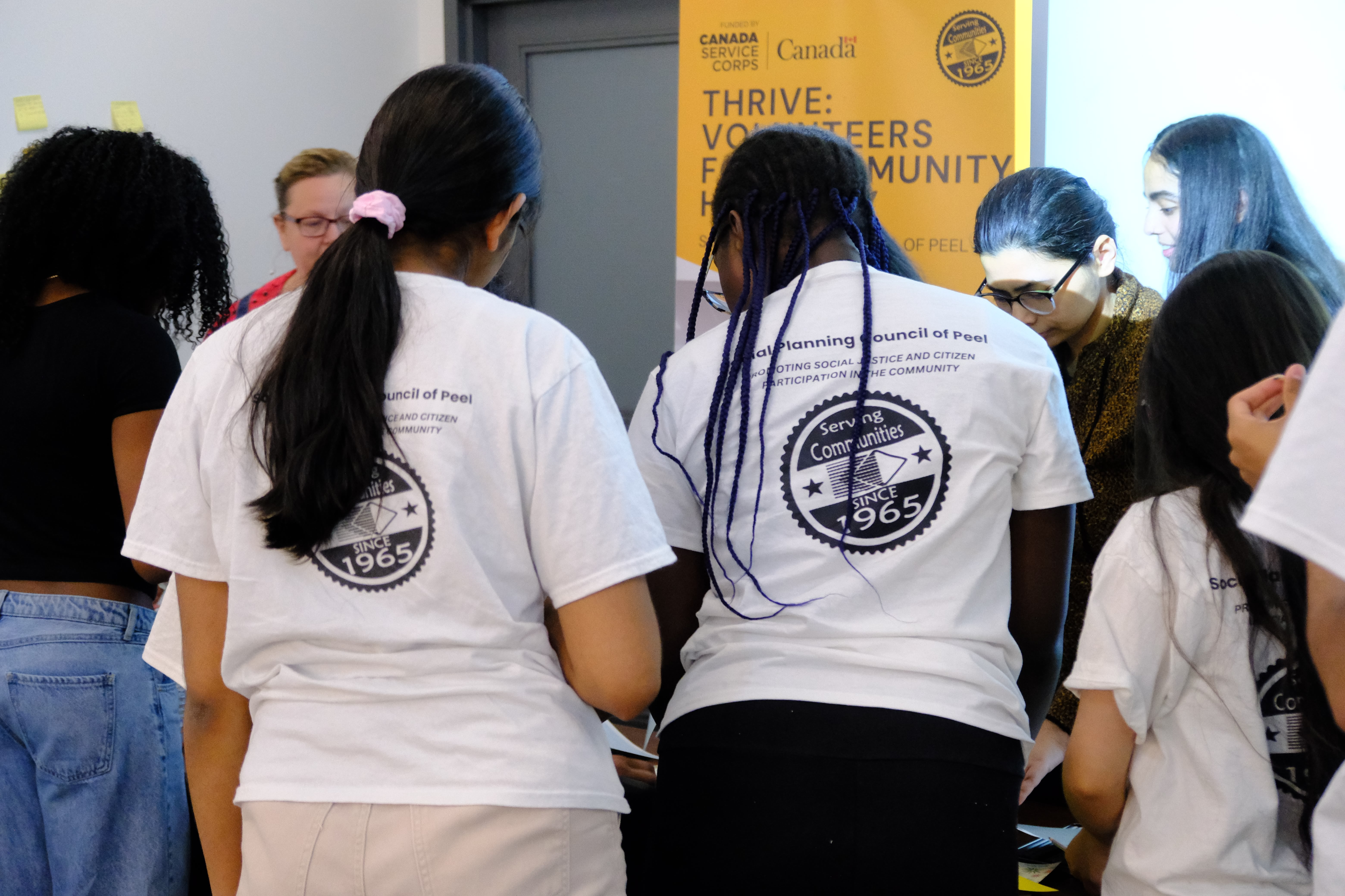A closeup picture of various youths wearing t-shirts with SPCP logo and interacting with each other during the Learning How to Practice Community Workshop with Dr. Bethany Osborne on June 3, 2025