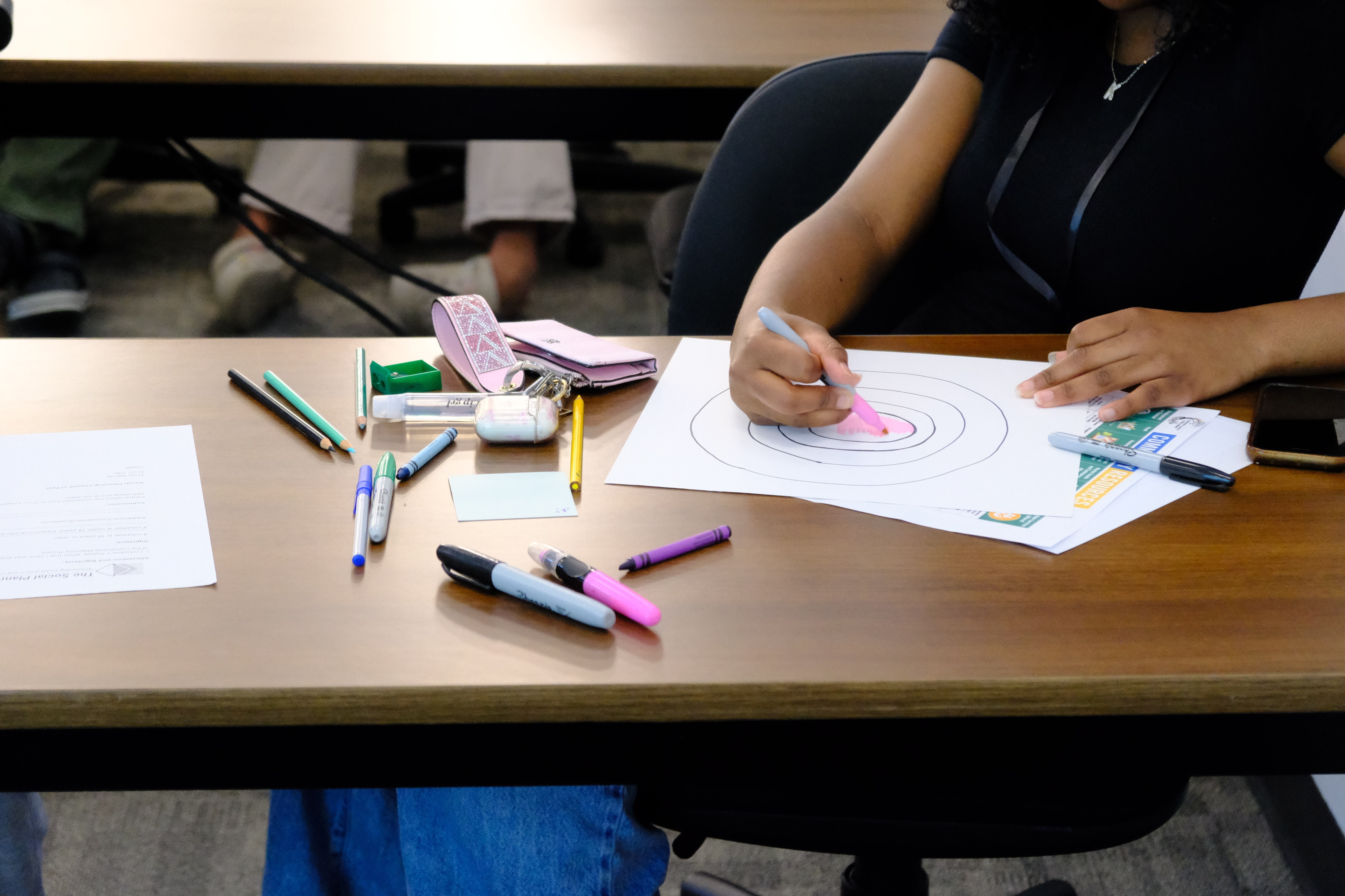 A closeup picture of a youth coloring various circles on a paper as part of the Learning How to Practice Community Workshop with Dr. Bethany Osborne on June 3, 2025