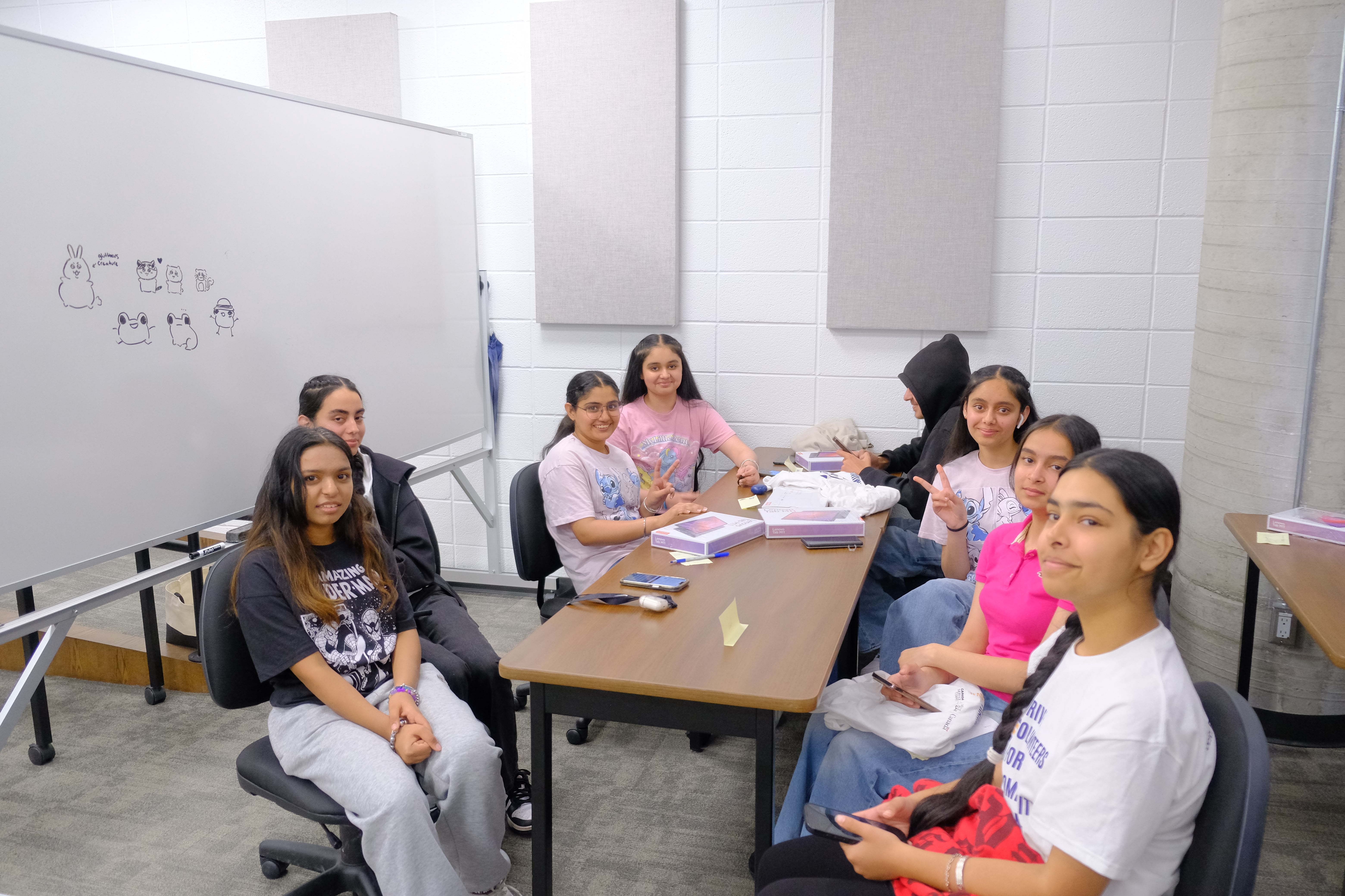 A picture of a group of youths across a table during the the Entrepreneurship Basics Workshop explaining to the youths on May 24, 2025