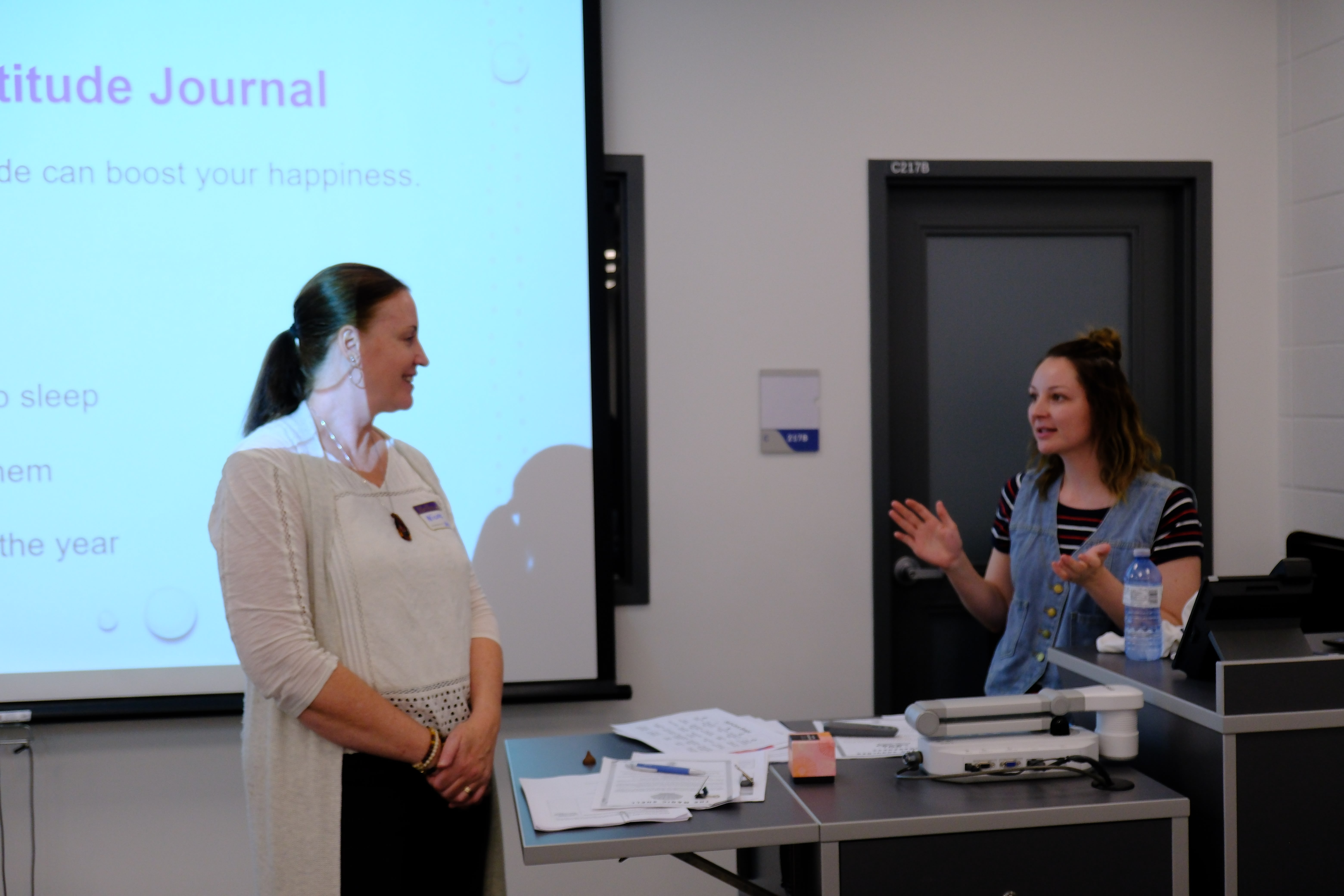A closeup picture of a youth and the Facilitator interacting with each other in front of the projector during the Mental & Physical Wellness Workshop with Nicole Johnson on May 27, 2025