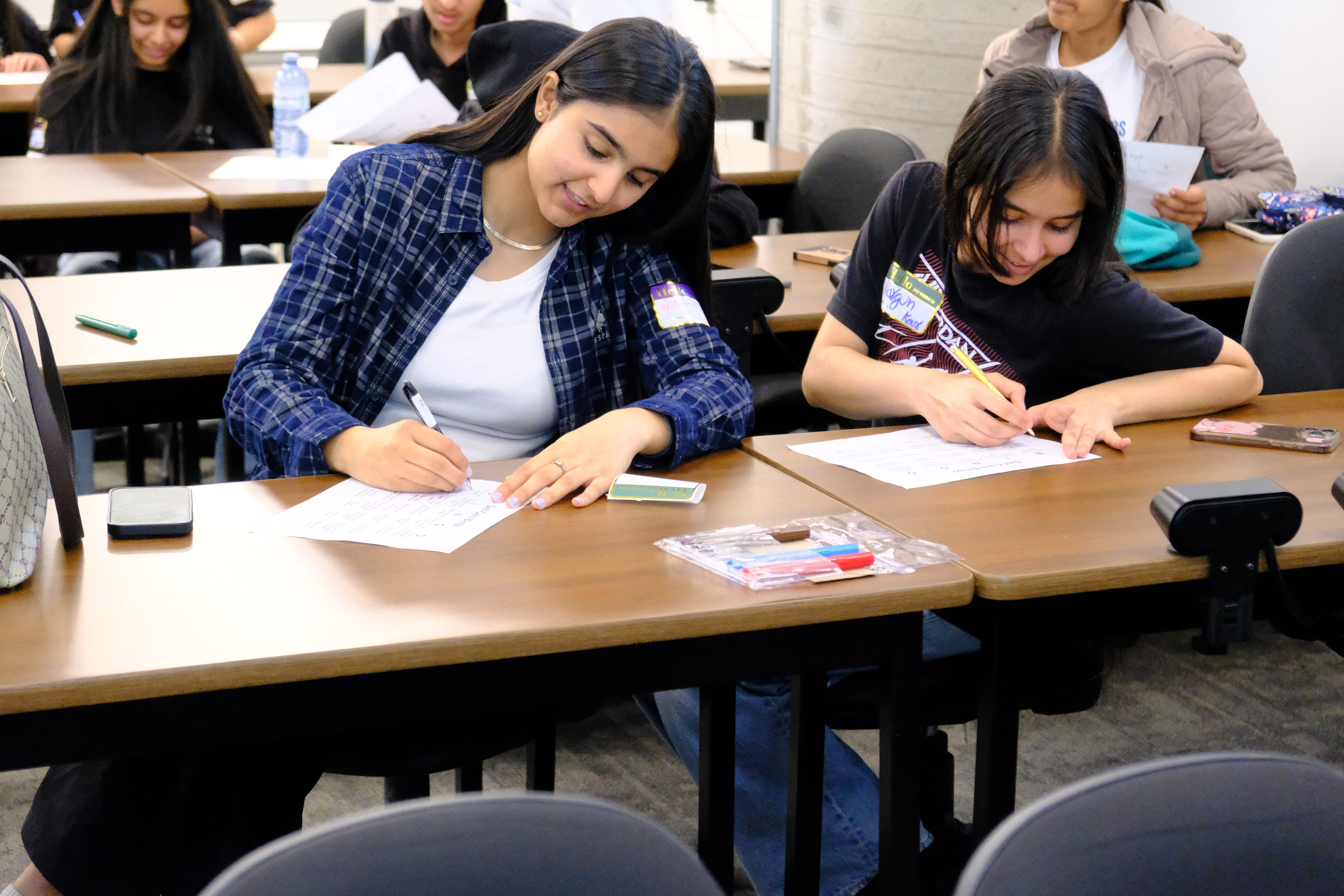 A closeup picture of a couple of youths focused on completing tasks given during the Mental & Physical Wellness Workshop with Nicole Johnson on May 27, 2025
